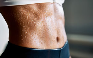 Ripped abs of a young woman covered in swat after her morning workout