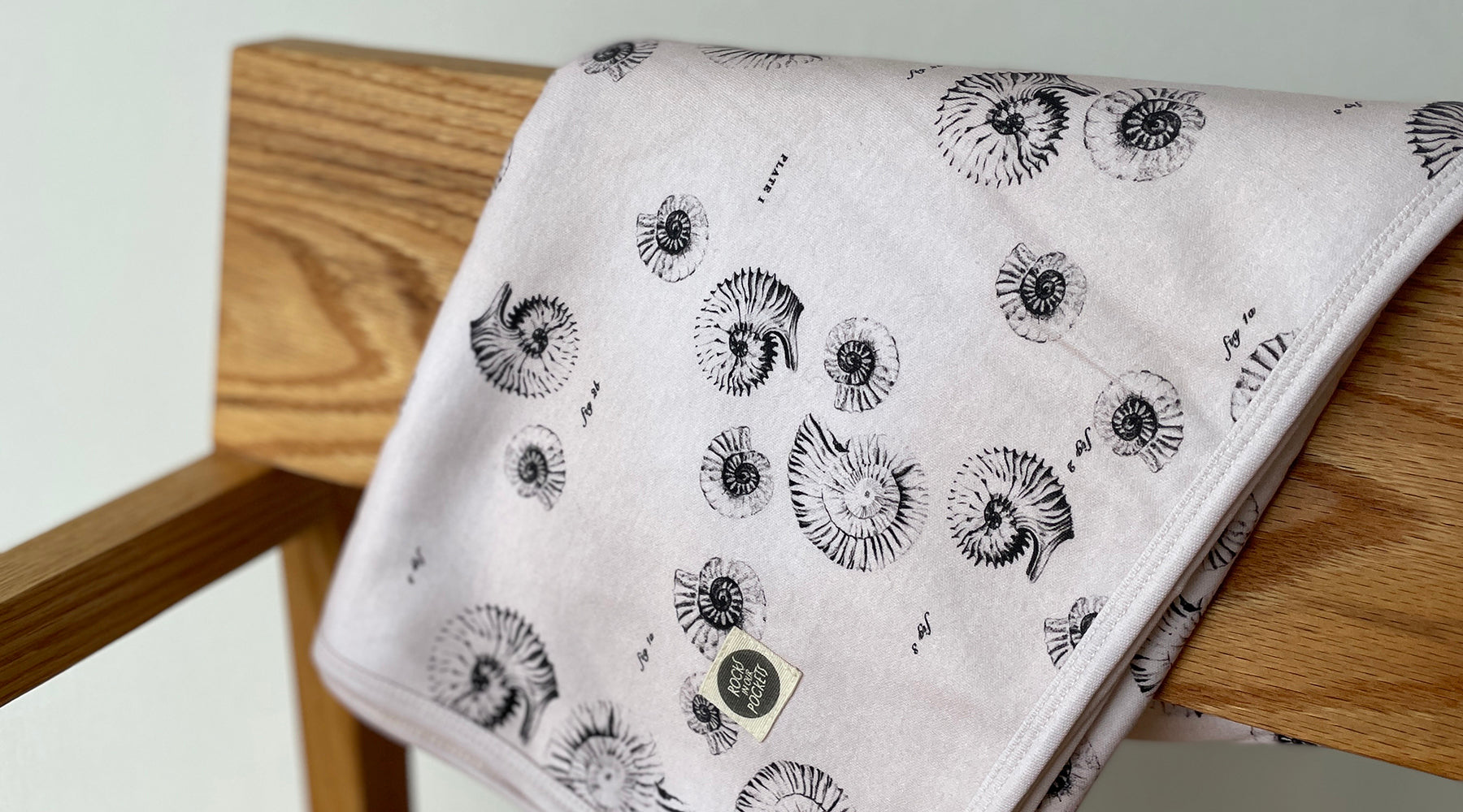 pink jersey blanket with ammonite print on a chair