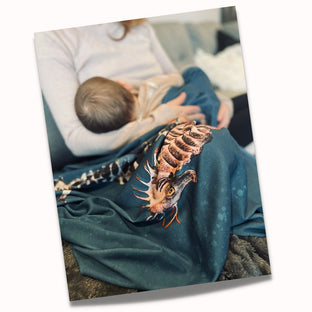 mother breastfeeding a baby with a teal coloured blanket on her lap