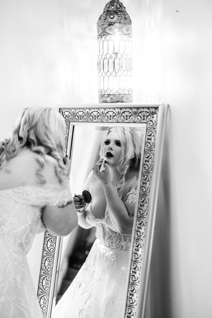Chantelle applies her lipstick in the reflection of an ornate mirror, lit by a glowing vintage lantern.