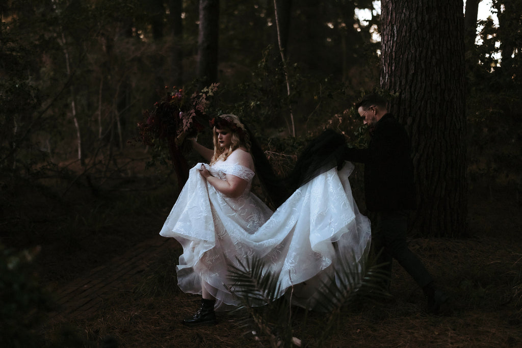 Dave carries Chantelle's cathedral length train as they wander through the forest. Chantelle lifts her hem to reveal patent-leather boots.