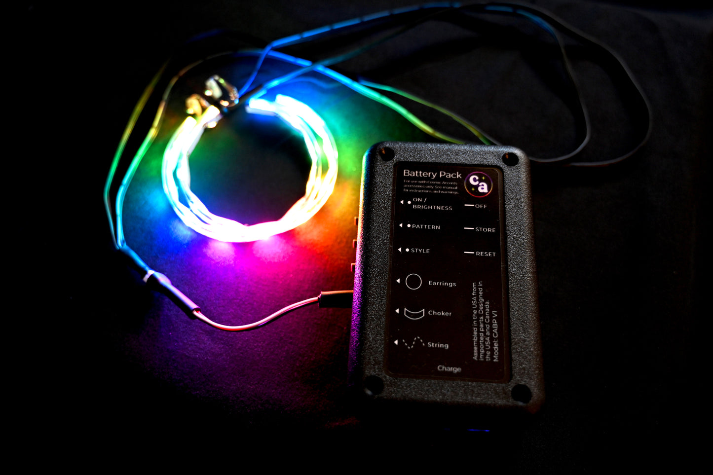 battery pack operating a pair of led earrings, showing wires connecting to battery pack on black background
