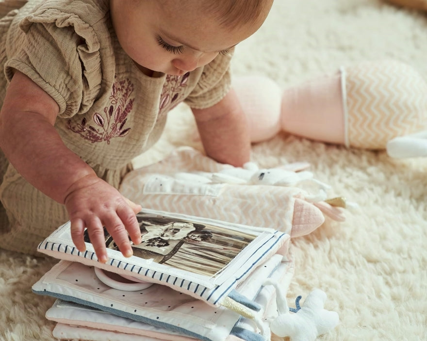 Baby betrachtet ein Fotoalbum mit einem Stoffeinband