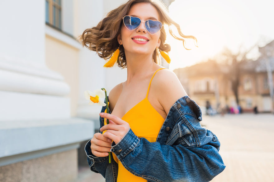 Das Mädchen lächelt auf der Straße trägt ein gelbes Kleid und eine Sonnenbrille
