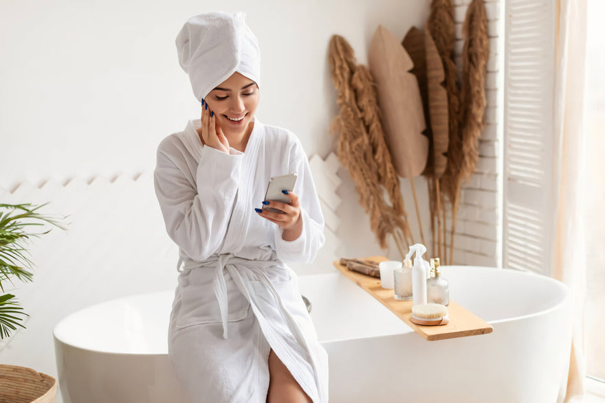 Frau im Bademantel sitzt auf der Badewanne im Spa