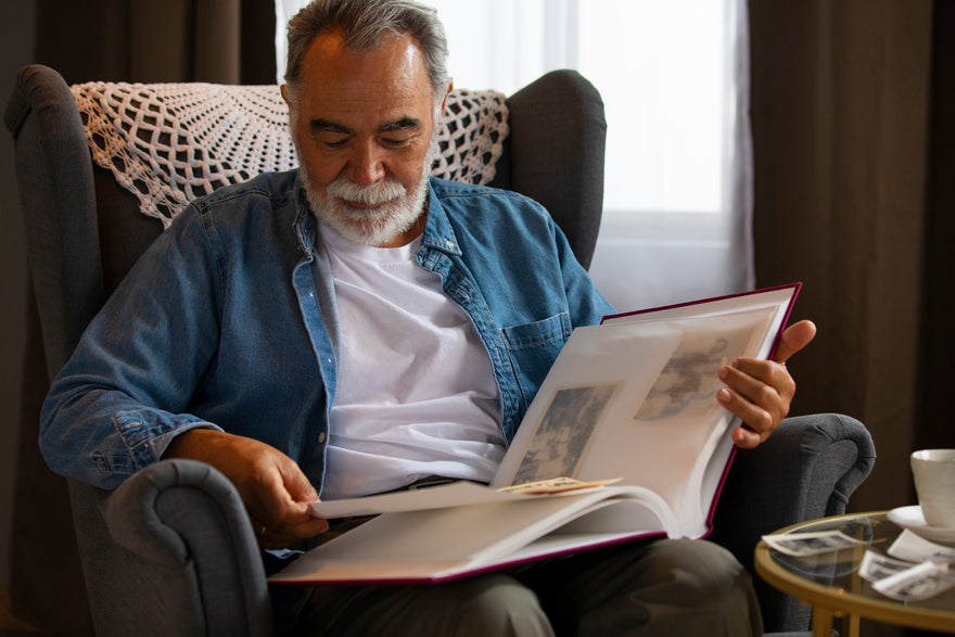 Ein alter Mann mit einem Fotoalbum sitzt in einem Sessel