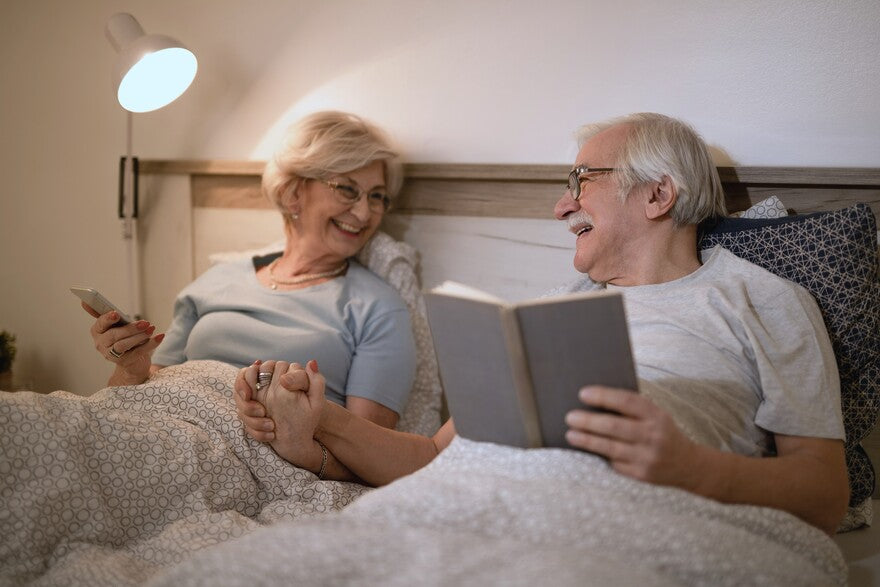 Ein altes Paar im Bett mit Buch lesen lächeln