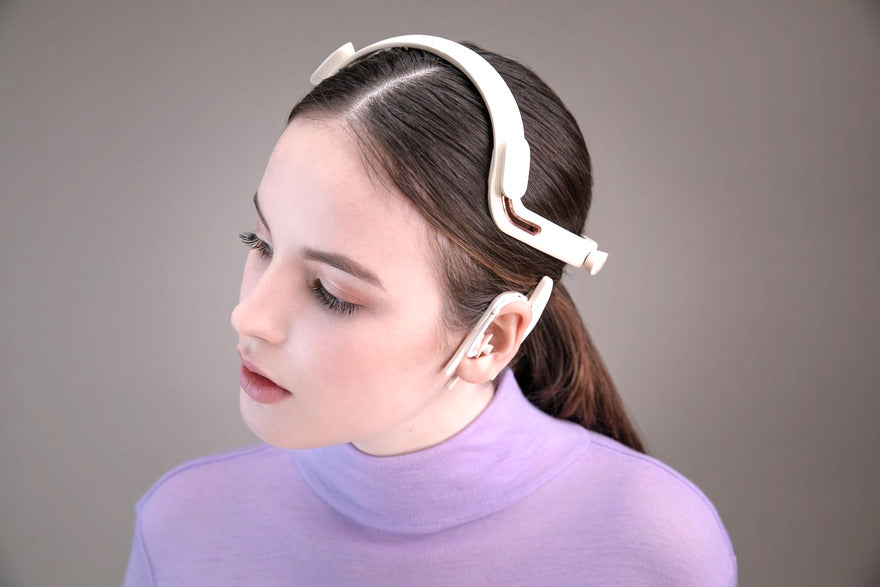 Eine Frau in einem lila Hemd mit einem Hörgerät auf einer Seite ihres Gesichts
