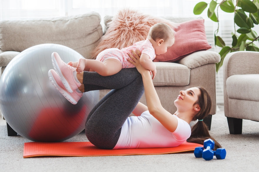 Junge hübsche Mutter macht Yoga mit ihrem kleinen Mädchen zu Hause