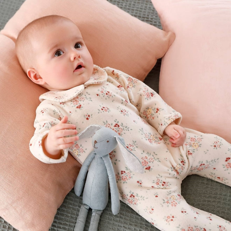 Baby Mädchen trägt das rosafarbenen Strumpelanzug mit Blumen