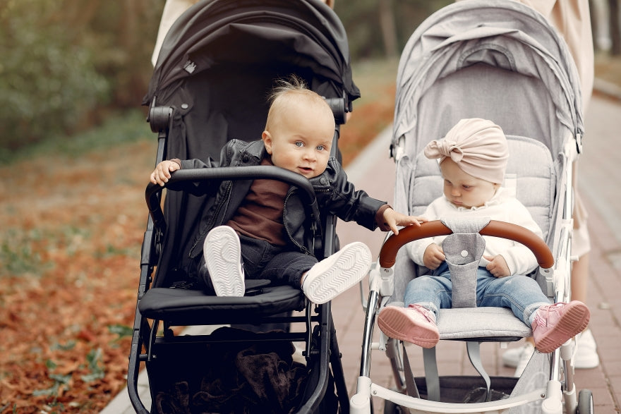 Zwei jung Mütter wandern im Herbstpark mit Babys Laufschuhen