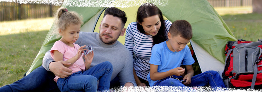Family of 4, 2 adults and 2 children, laying on the grass outdoors for outdoor camping activities