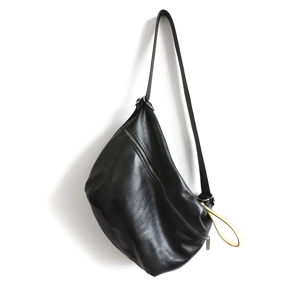 Grete pebble leather shoulder bag in black / caramel with red edge