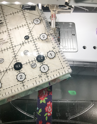 Acrylic quilting ruler placed over the batting leaning on a sewing machine