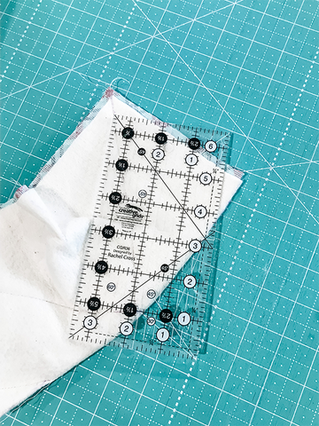 Quilting ruler on top of the corner of sewn batting and fabric piece