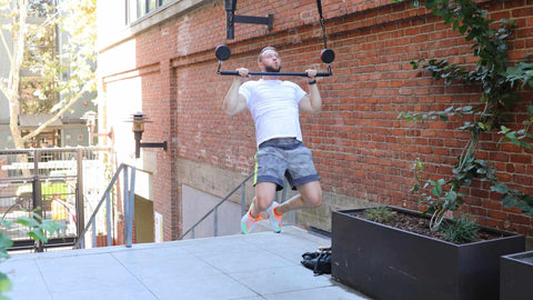 Personal trainer using the BGR bars grips rings to do a muscle pull up strength training exercise. Man doing outdoor exercise