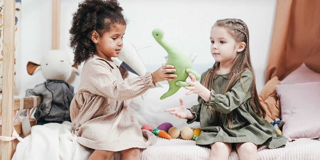 Two kids sharing a toy dinosaur