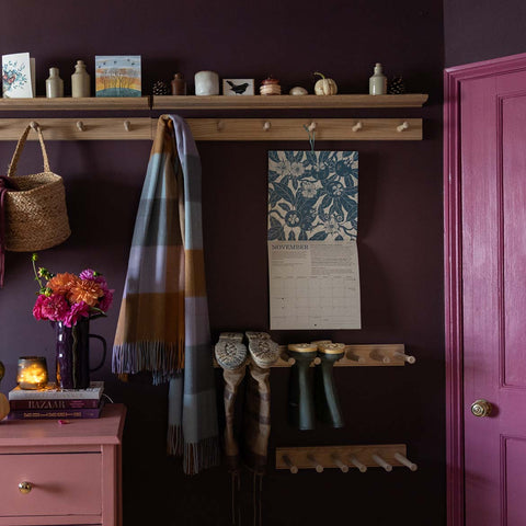 Bootroom scene featuring a colour scheme of pink and purple and our british made oak welly boot racks and peg rails with picture ledges above 