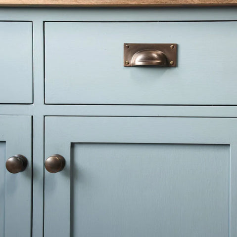 Distressed antique brass cabinet fittings on pale blue cabinet