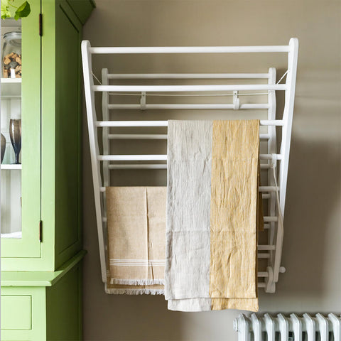 White wooden clothes airer hung on wall in laundry room