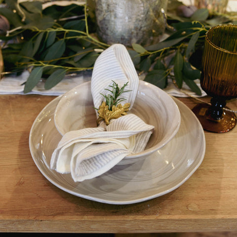 Placesetting with neutral bowls, napkin, brass napkin ring and rosemary sprig