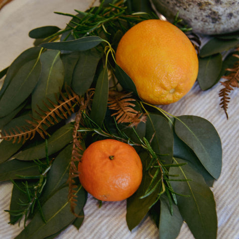 Oranges and foliage wuith candles on table