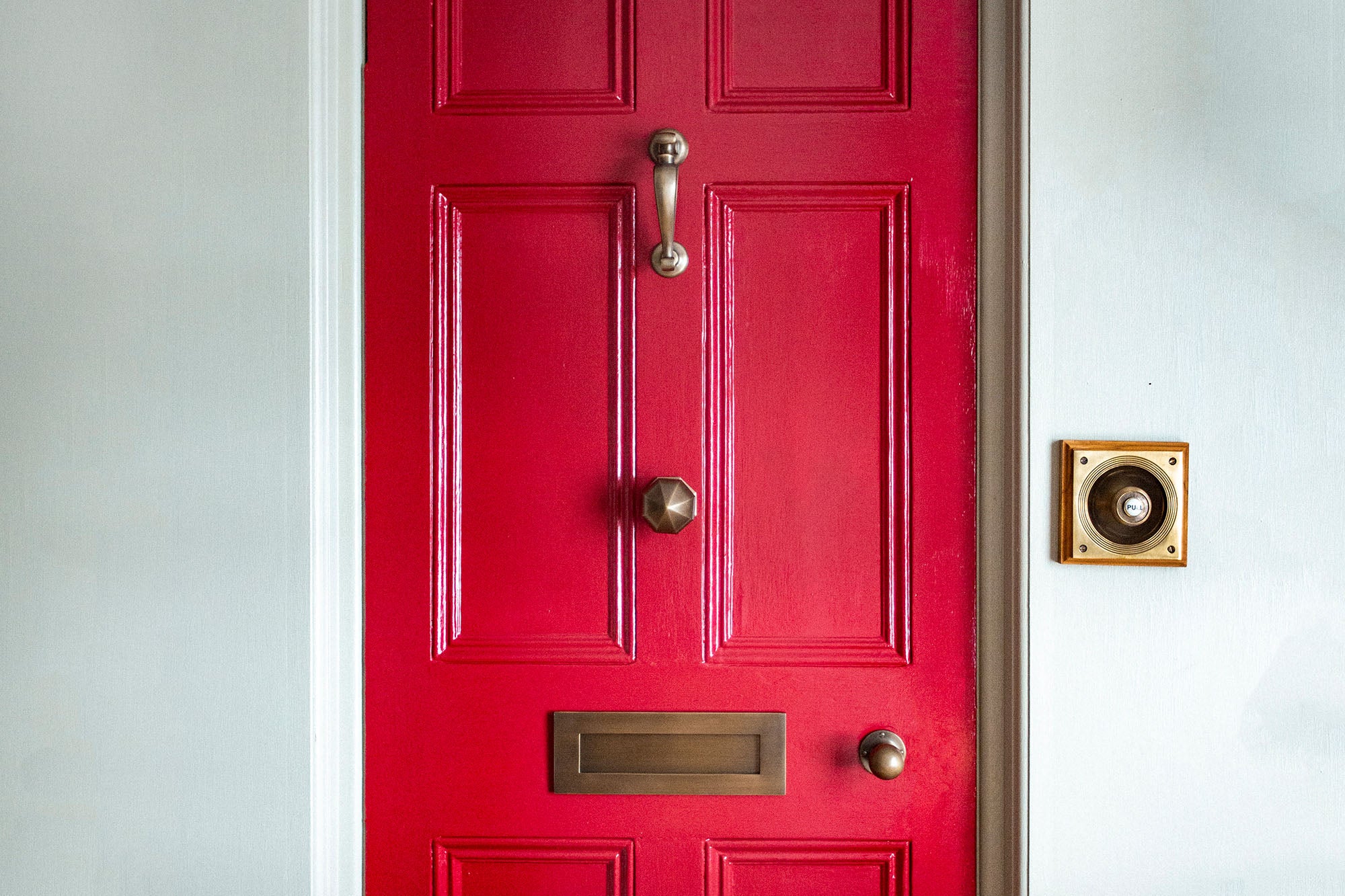 light antique brass door furniture on red door