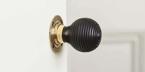 Solid ebony door knob on pale beige door