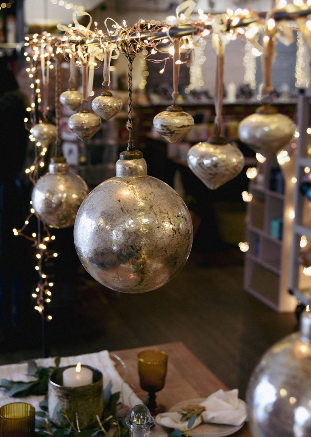 Table frame with a selection of large and small baubles hanging over festive table