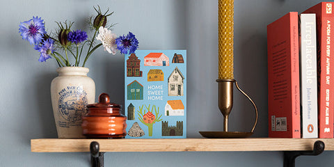 university room shelf with books, candle and home sweet home card