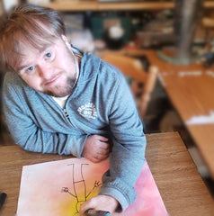 Disabled artist Fionn in art studio looking into camera