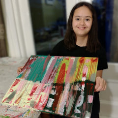 Disabled artist, Ella Evenson proudly showing off her artwork. Big smile.