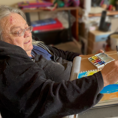 disabled artist Ceridwen Powell painting artwork at home in studio