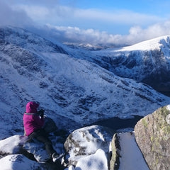 Artist with disability Sarah Forbes taking a photograph of a welsh mountain range in the snow