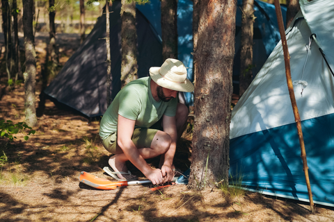 man setting up tent with wide brimmed hat