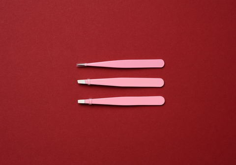 pink tweezer with red background