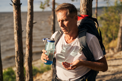 man drinking bottle of water while on hike