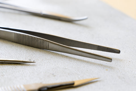 closeup shot of curved tweezer on wooden table