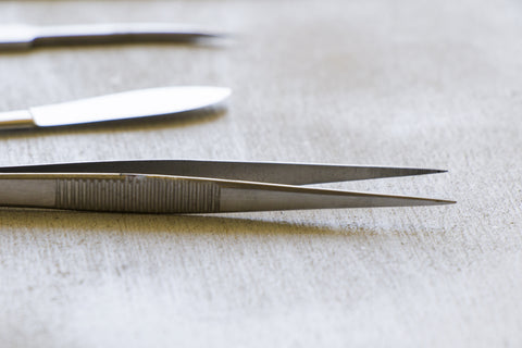 closeup shot of pointed tweezers on wooden table