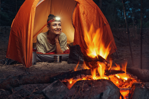 happy woman in orange tent with torch on head