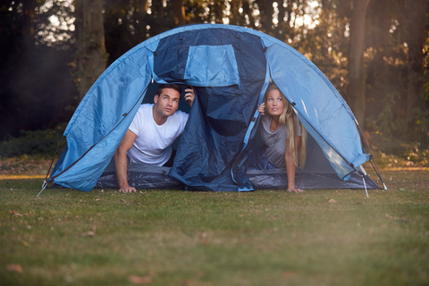 man and woman opening tent and looking at rain outside