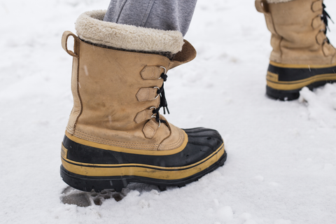 leg with brown boots walking in snow