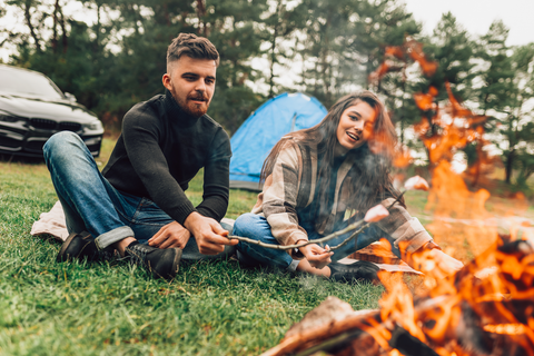 man and woman sitting at campsite infront of campfire