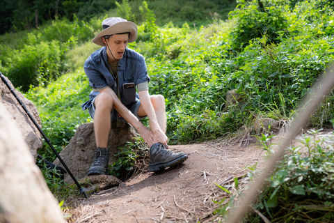 man sitting on rock with an injured ankle