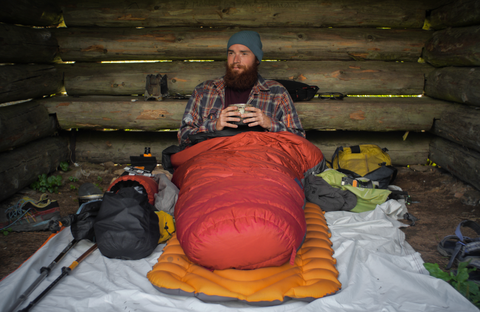 man in cabin with red sleeping bag