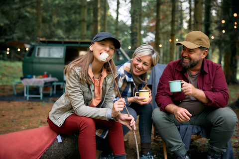 happy family at a campsite drinking a hot drink and marshmallows