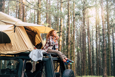 woman sitting in tent on car roof