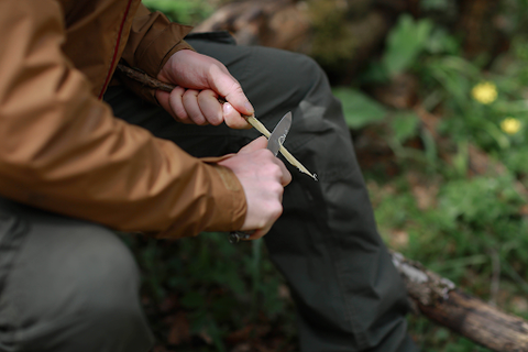 using a knife to cut wood on camp site