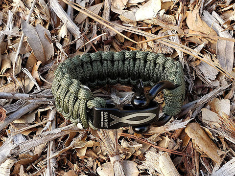 A simple Savior Survival Gear Paracord Bracelet in kaki lying in some dry leaves and bark