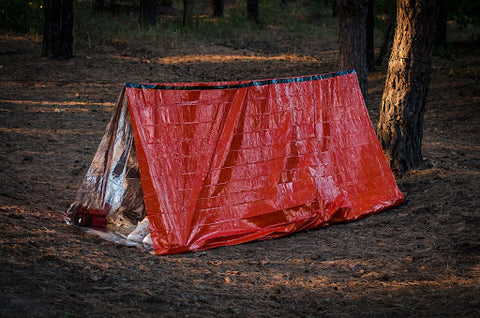 An Emergency USA red shelter tent in a sandy area